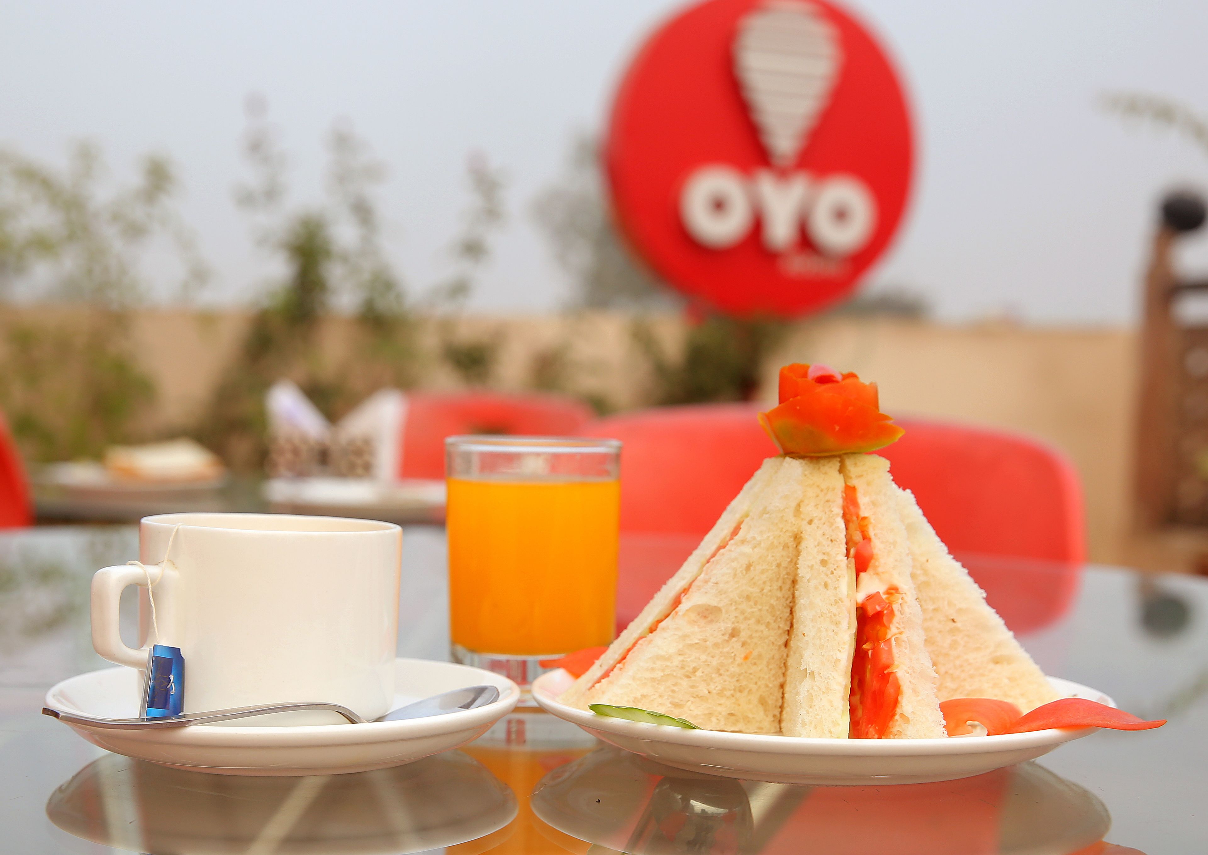 A table with a white mug, a glass of orange juice, and a sandwich on a plate.