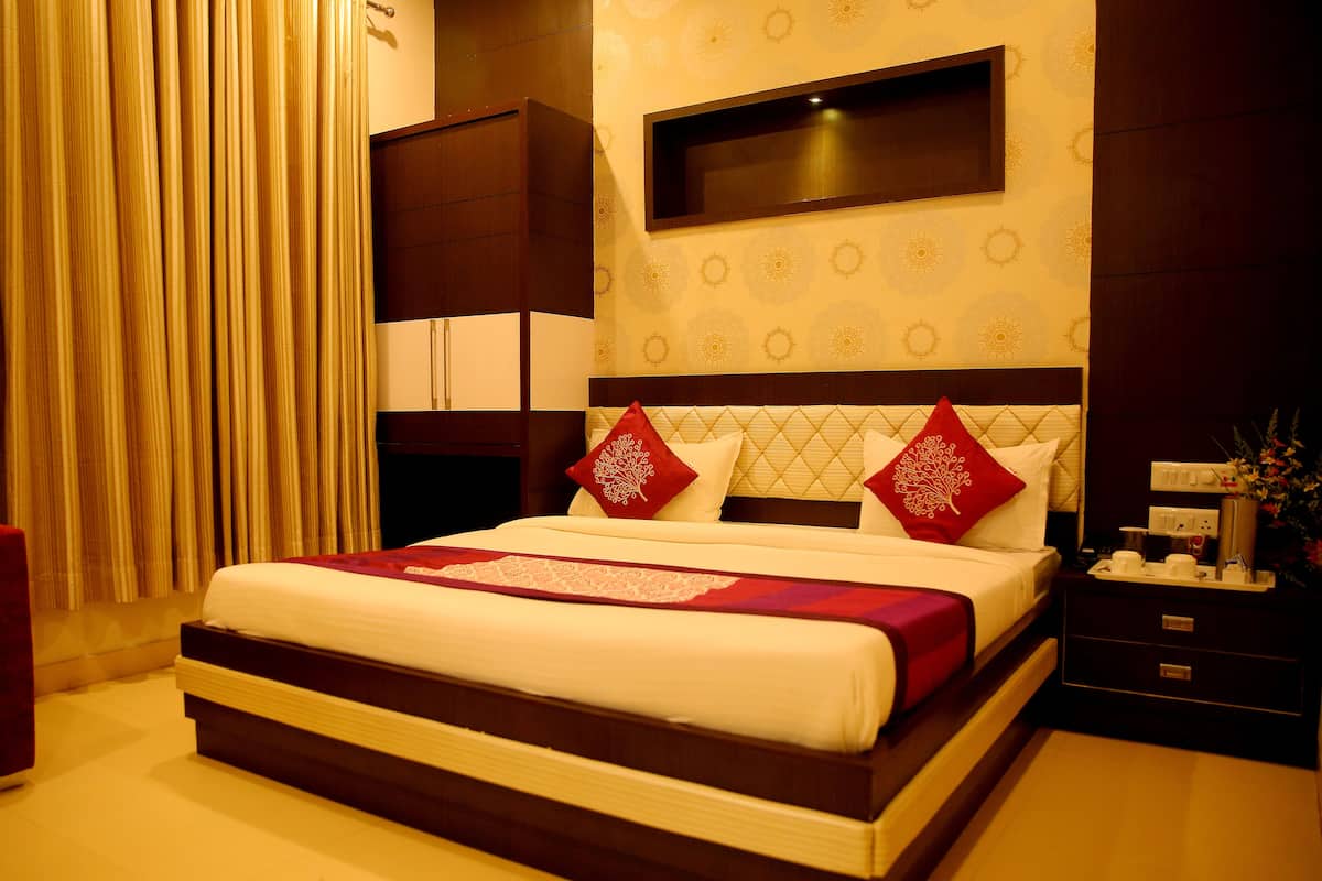 A hotel room with a large bed, a bedside table, a nightstand, and a wall-mounted TV.