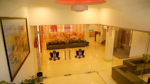 A modern hotel lobby with a glass partition, a sofa, and a dining area. - Hotel Rivera Palace (Varanasi)