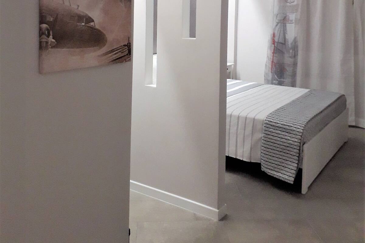 A modern bedroom with a bed, a painting on the wall, and a window with curtains.