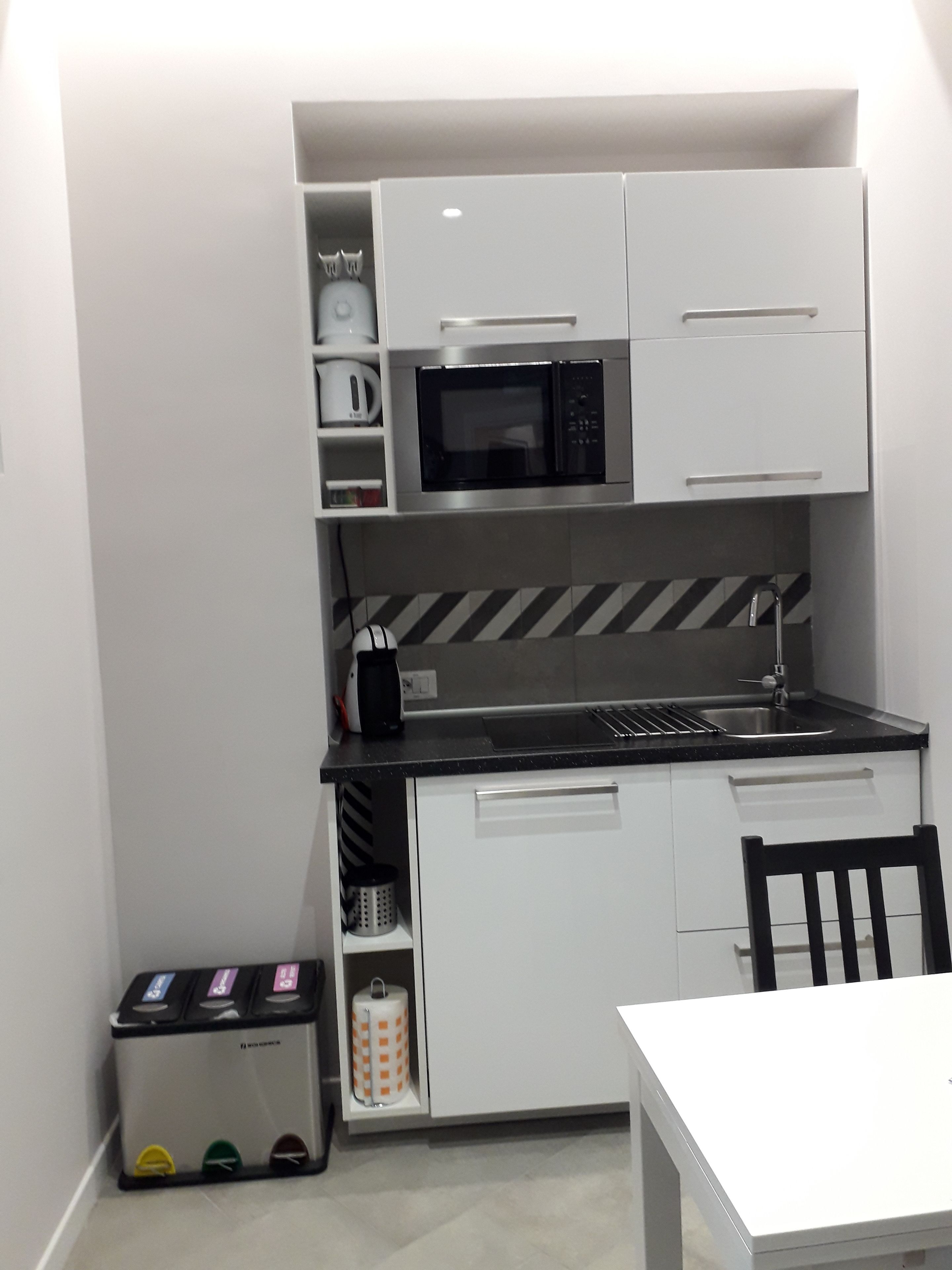 Une petite cuisine équipée d’un four à micro-ondes, d’un évier et de placards de rangement.