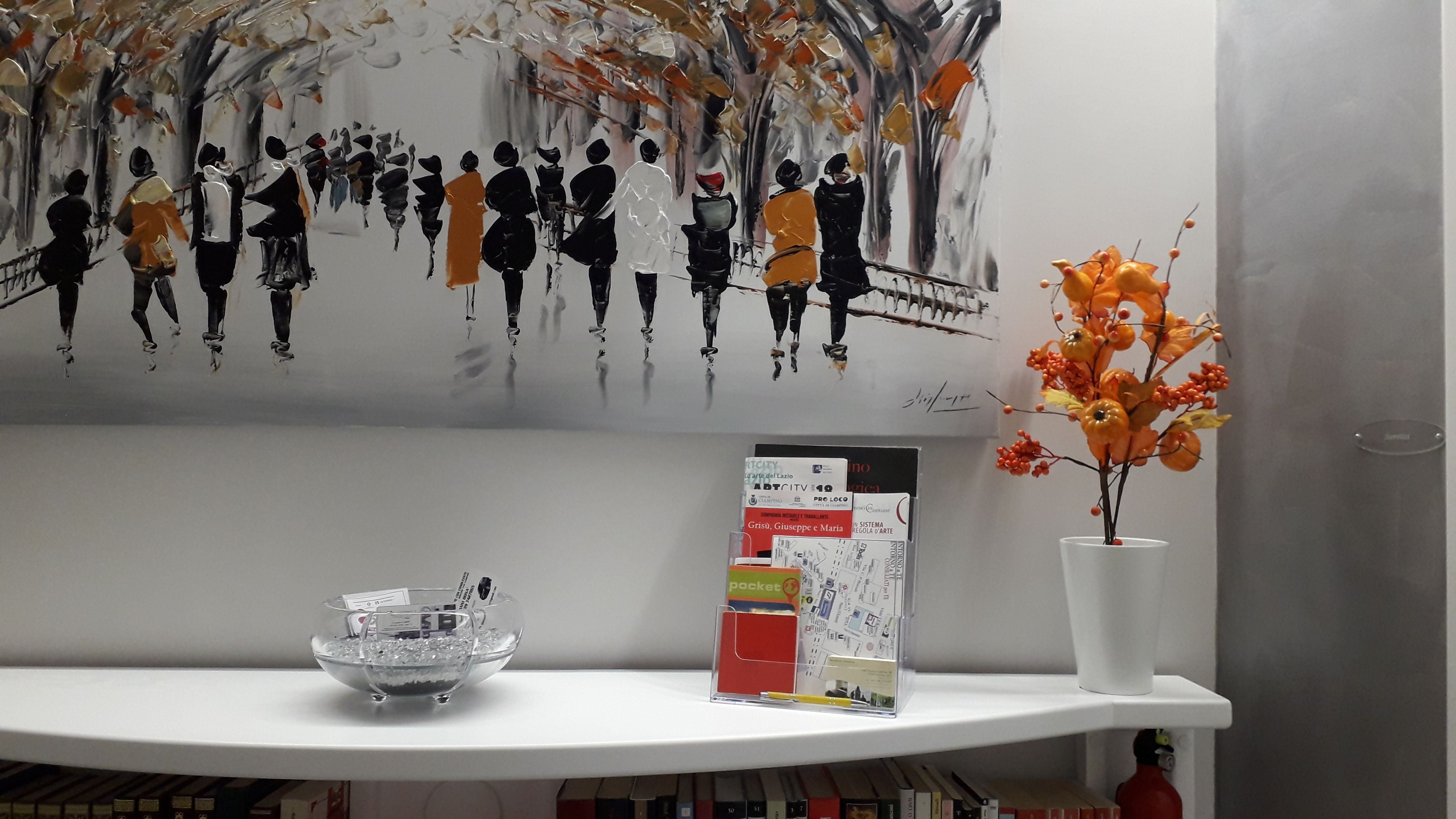 A shelf with a glass bowl, a booklet, and a vase with orange flowers.