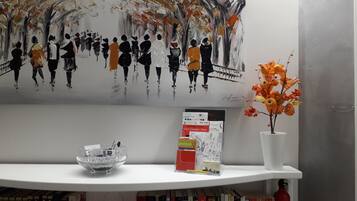 A shelf with a glass bowl, a booklet, and a vase with orange flowers.