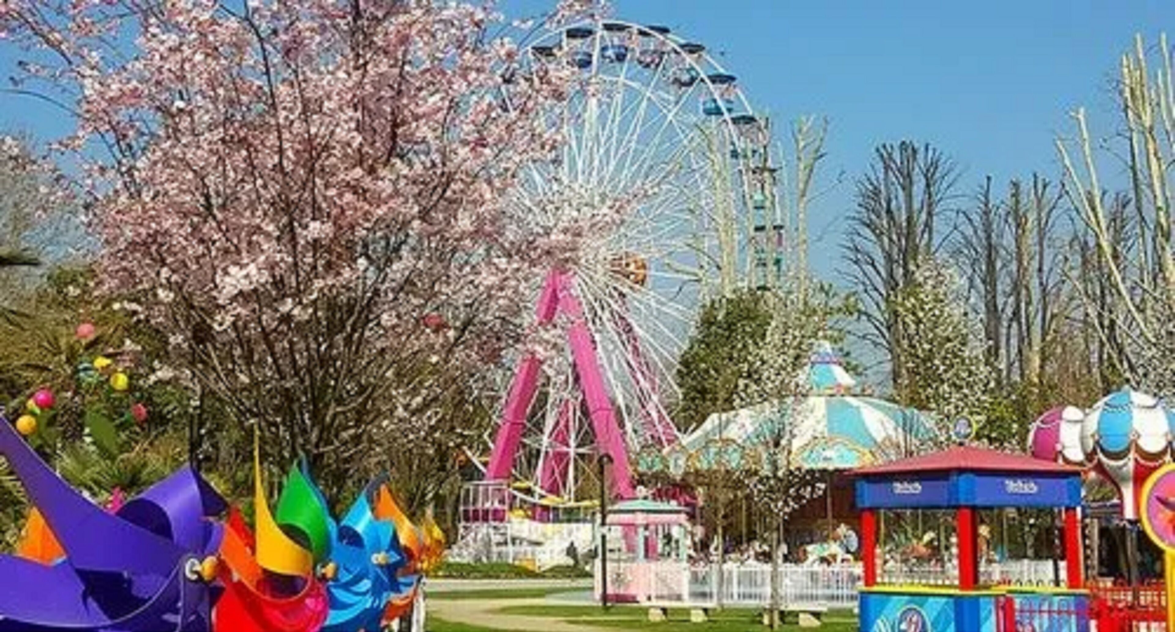 A Ferris wheel, a carousel, and a small booth with a blue roof.