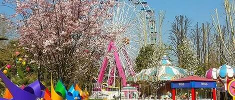 A Ferris wheel, a carousel, and a small booth with a blue roof.