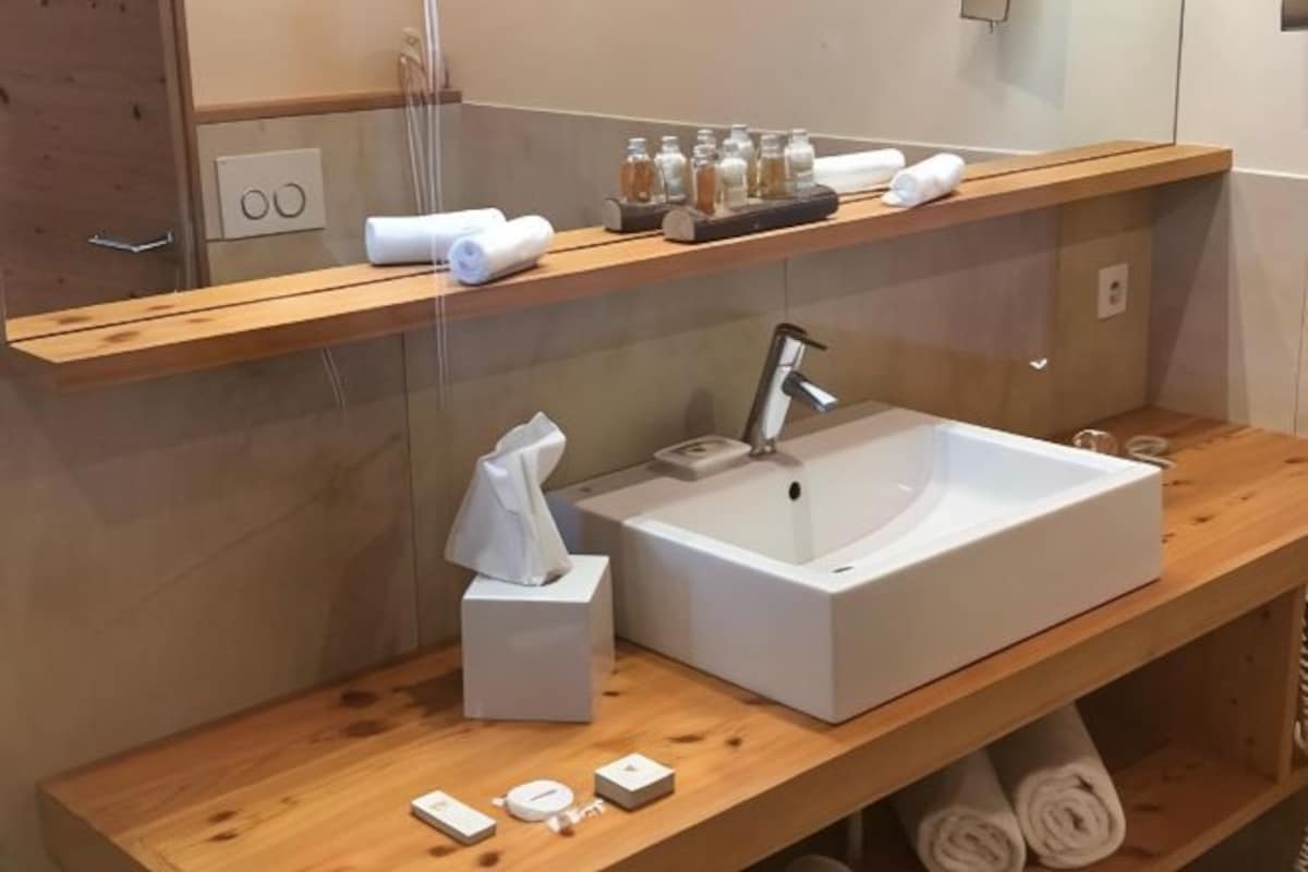 A modern bathroom with a large sink, wooden shelves, and a mirror.