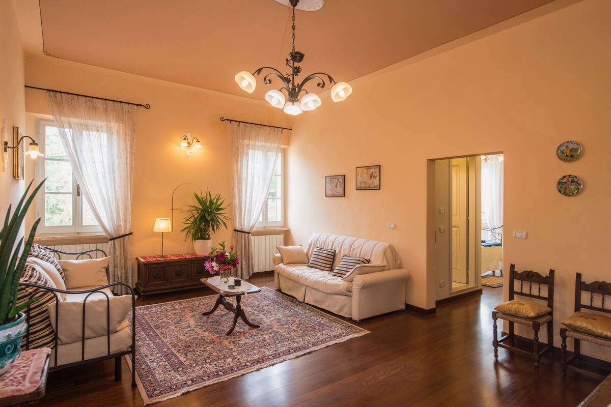 Een woonkamer met een bank, fauteuils, een salontafel en een kroonluchter.
