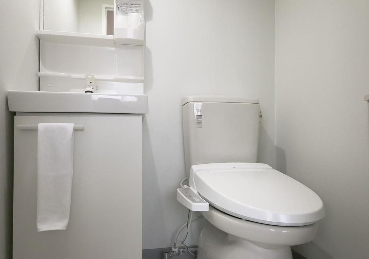 A white toilet with a control panel, a towel hanging on a rack, and a wall-mounted air freshener.