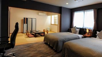 Habitación de hotel con dos camas, un escritorio, una silla y una puerta corredera japonesa tradicional.