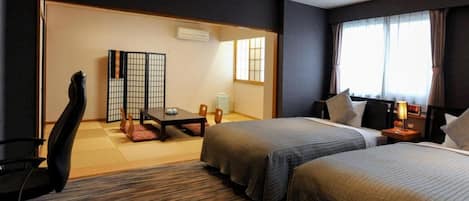 A hotel room with two beds, a desk, a chair, and a traditional Japanese sliding door.