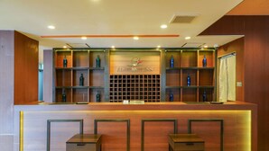 A reception desk with a wooden finish, two seating areas, and shelves with bottles. - REMBRANDT INN KAZUSA (Kimitsu)