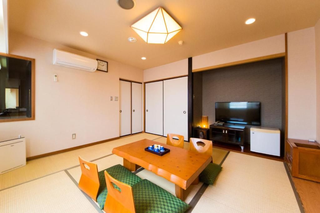 A traditional Japanese-style room with tatami flooring, a low table, and a television.