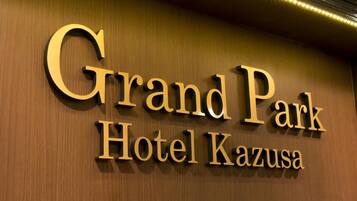 A sign for Grand Park Hotel Kazusa with a wooden background and illuminated lettering.