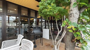 A restaurant with outdoor seating, a grill, and a tree. - REMBRANDT INN KAZUSA (Kimitsu)