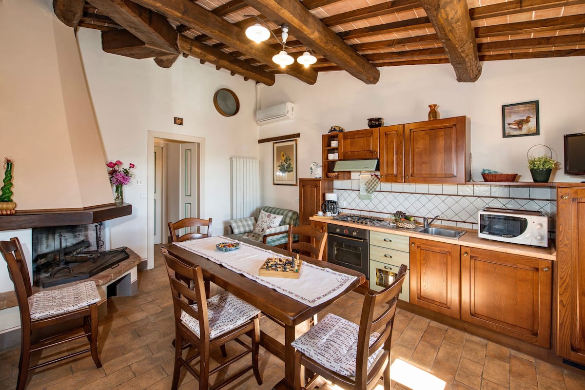 Una cocina rústica con armarios de madera, una mesa de comedor con sillas y una chimenea.