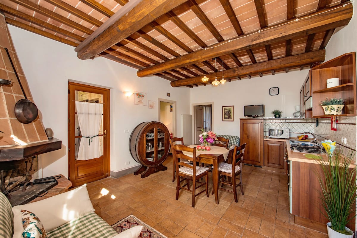 Una cocina acogedora con vigas de madera, un comedor con mesa y sillas, y una encimera con electrodomésticos.