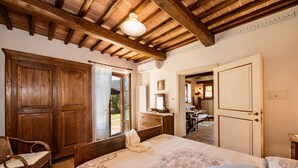 A bedroom with a large bed, wooden wardrobe, and a chair. - Agriturismo Malagronda (Citta della Pieve)
