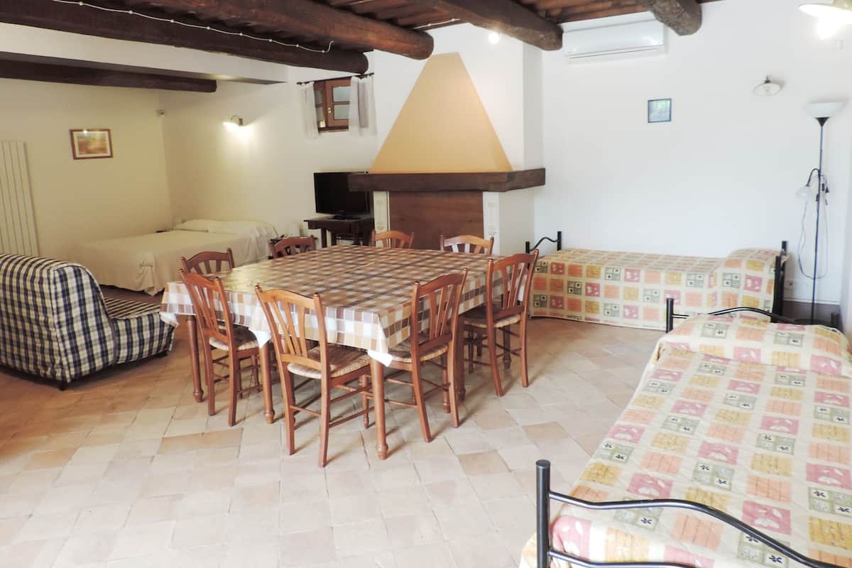 Una habitación acogedora con una mesa de madera, sillas, un sofá y una cama.