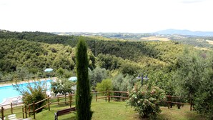 A pool with a wooden deck and a view of a forested valley. - Agriturismo Malagronda (Citta della Pieve)