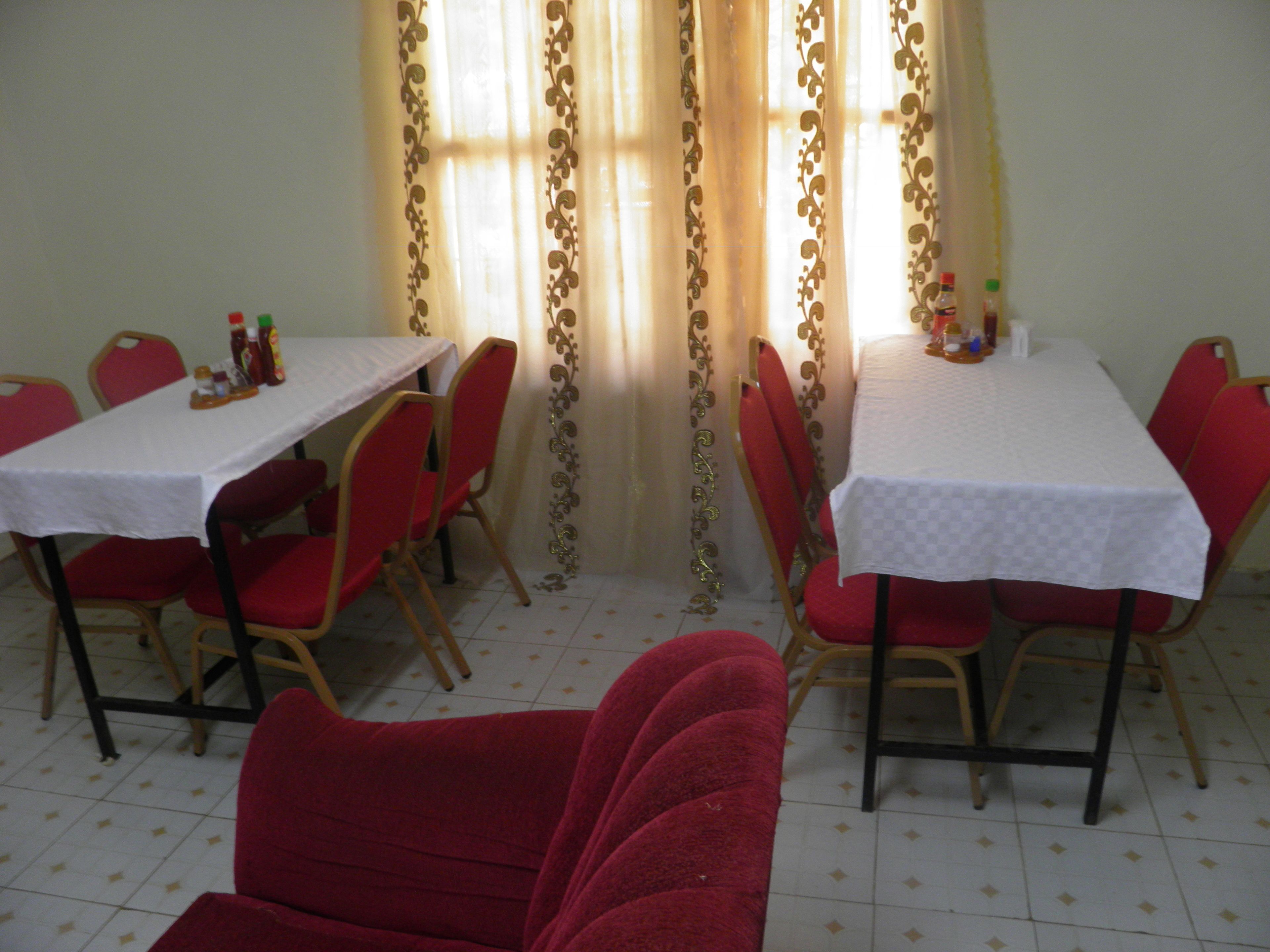 A dining area with two tables, red chairs, and a decorative curtain.