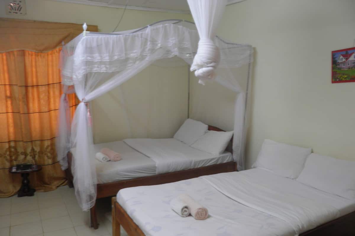 Quarto com cama de dossel, uma cama menor e uma mesa de cabeceira com abajur.