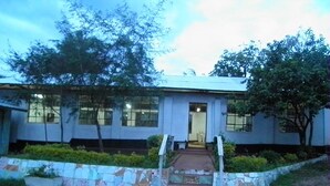 A building with a stone pathway leading to a door, surrounded by greenery and trees. - Imani Radio & TV Ministries (Kitale)
