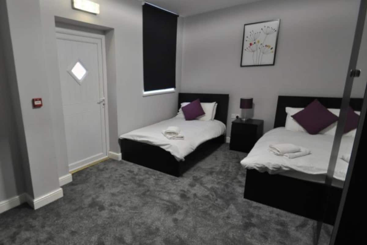 A hotel room with two beds, a desk, and a chair.