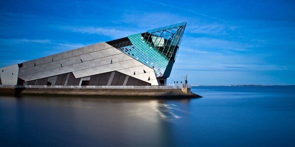 A modern architectural building with a unique angular design, situated by a calm body of water.