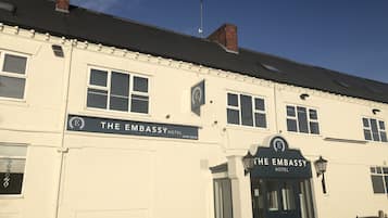 A white building with a sign reading "The Embassy Hotel".