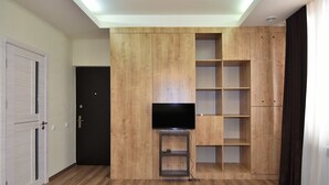 Um quarto com um móvel de entretenimento de madeira, uma TV de tela plana e uma porta.