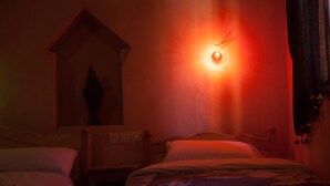 A dimly lit room with two beds, a wall-mounted light, and a small window. - Kasbah Ait Kassi (Souk Lakhmis Dades)