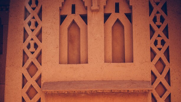 A building entrance with a large arched doorway, decorative lattice patterns, and a stone base. - Kasbah Ait Kassi (Souk Lakhmis Dades)