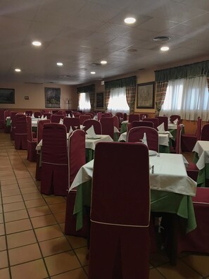 A banquet hall with rows of tables and chairs, each set with white tablecloths and red chairs. - Hotel Mesón del Moro (Abaran)