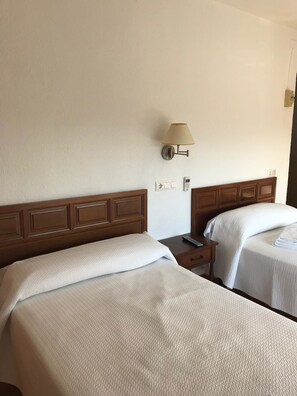 A hotel room with two beds, a nightstand, a lamp, and a phone on the wall. - Hotel Mesón del Moro (Abaran)