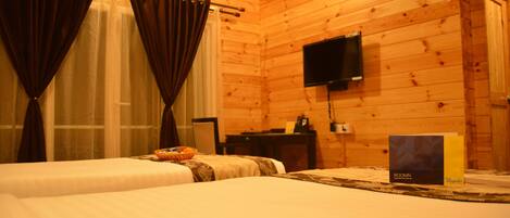 A wooden cabin room with two beds, a television, and a box labeled "ROOMIN."