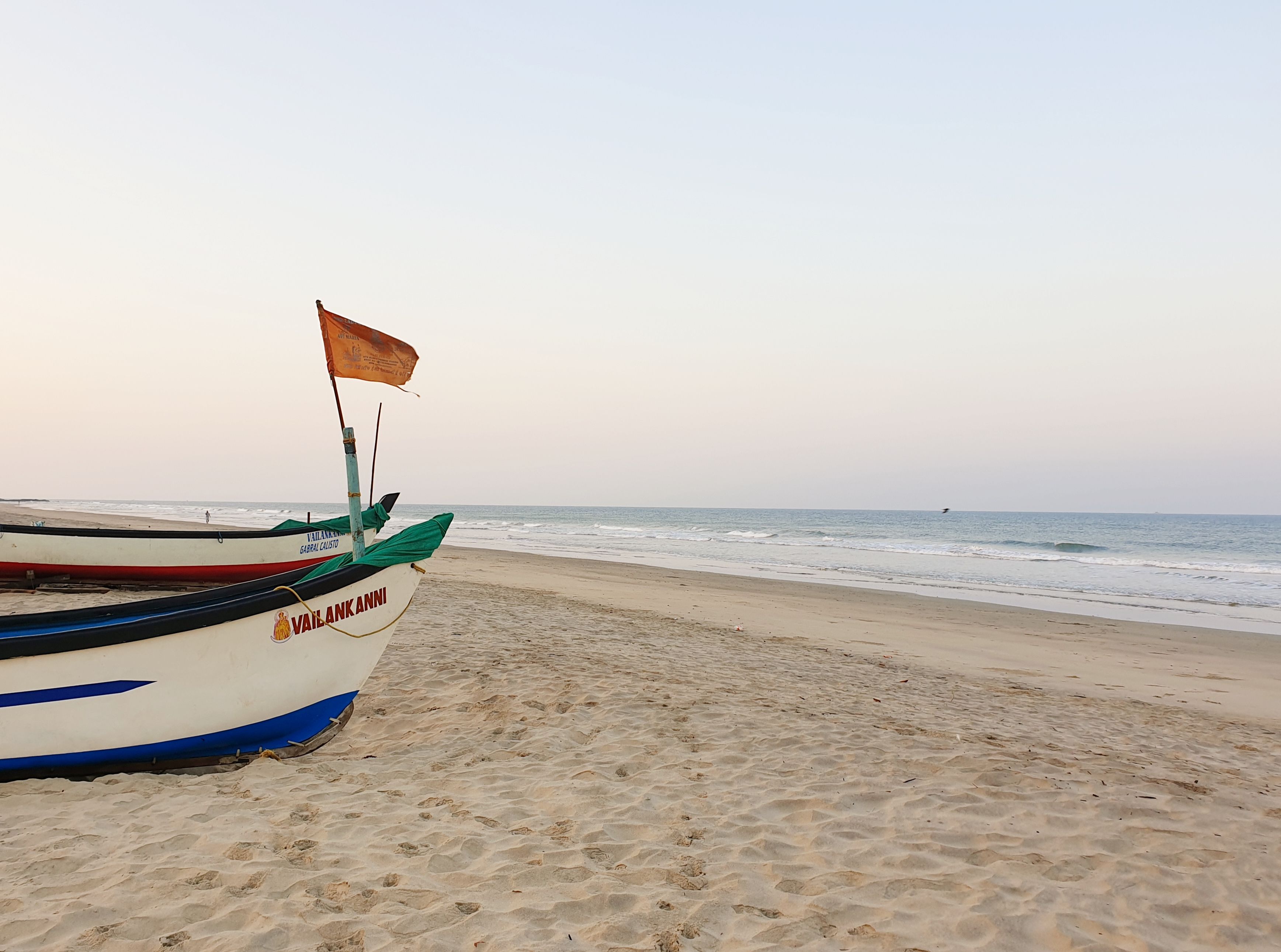 A beach with a boat named "Vailankanni" anchored on the sand.