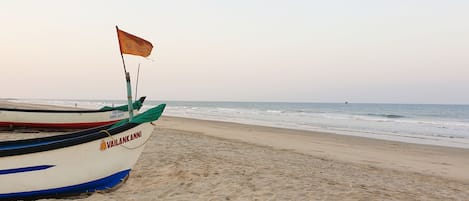 A beach with a boat named "Vailankanni" anchored on the sand.