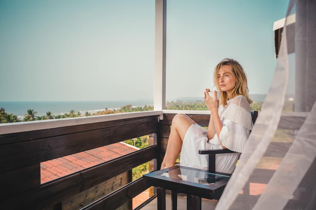 A person sitting on a balcony with a view of the sea.