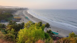 A beach with a row of huts and a clear view of the ocean. - The Regalia Resort (Ashvem)