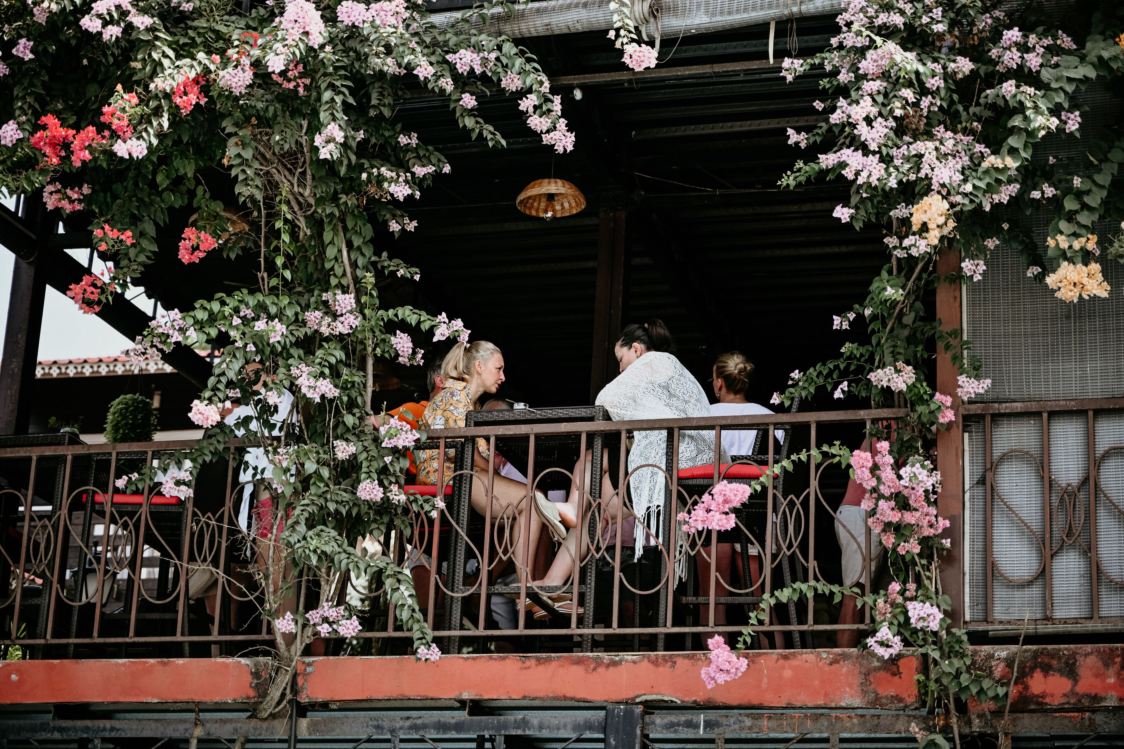 An outdoor seating area with tables and chairs, surrounded by a metal railing.