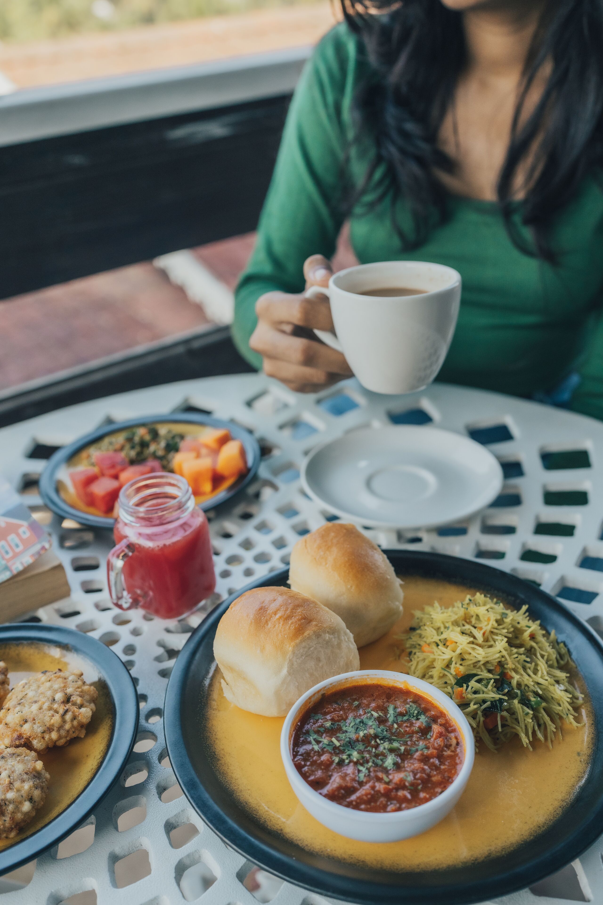 A dining table with various dishes including bread, a bowl of sauce, and a plate of vegetables.