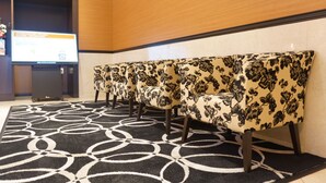 A row of upholstered chairs with a floral pattern, arranged in a waiting area with a patterned carpet.