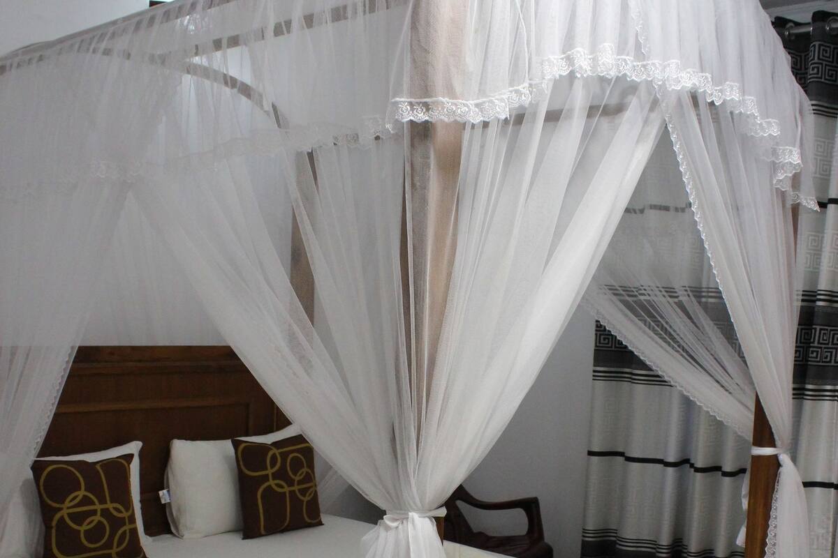 Un lit à baldaquin, avec des oreillers et une couverture.