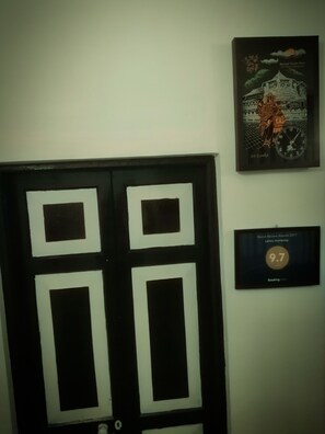 A door with a black and white design, a framed clock, and a framed certificate on the wall.