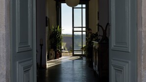 A hallway with a large window at the end, leading to a view of a landscape.