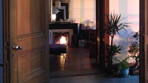 A warmly lit living room with a fireplace, a large mirror, and potted plants.