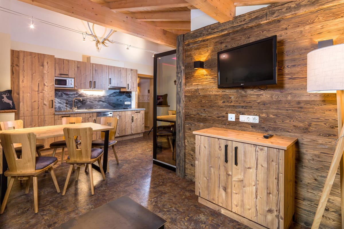 A modern kitchen with wooden cabinets, a built-in microwave, and a large TV mounted on the wall.