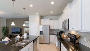 A modern kitchen with white cabinets, stainless steel appliances, and a black granite countertop. - Fv66383 - Windsor At Westside - 5 Bed 4.5 Baths Townhome (Kissimmee)