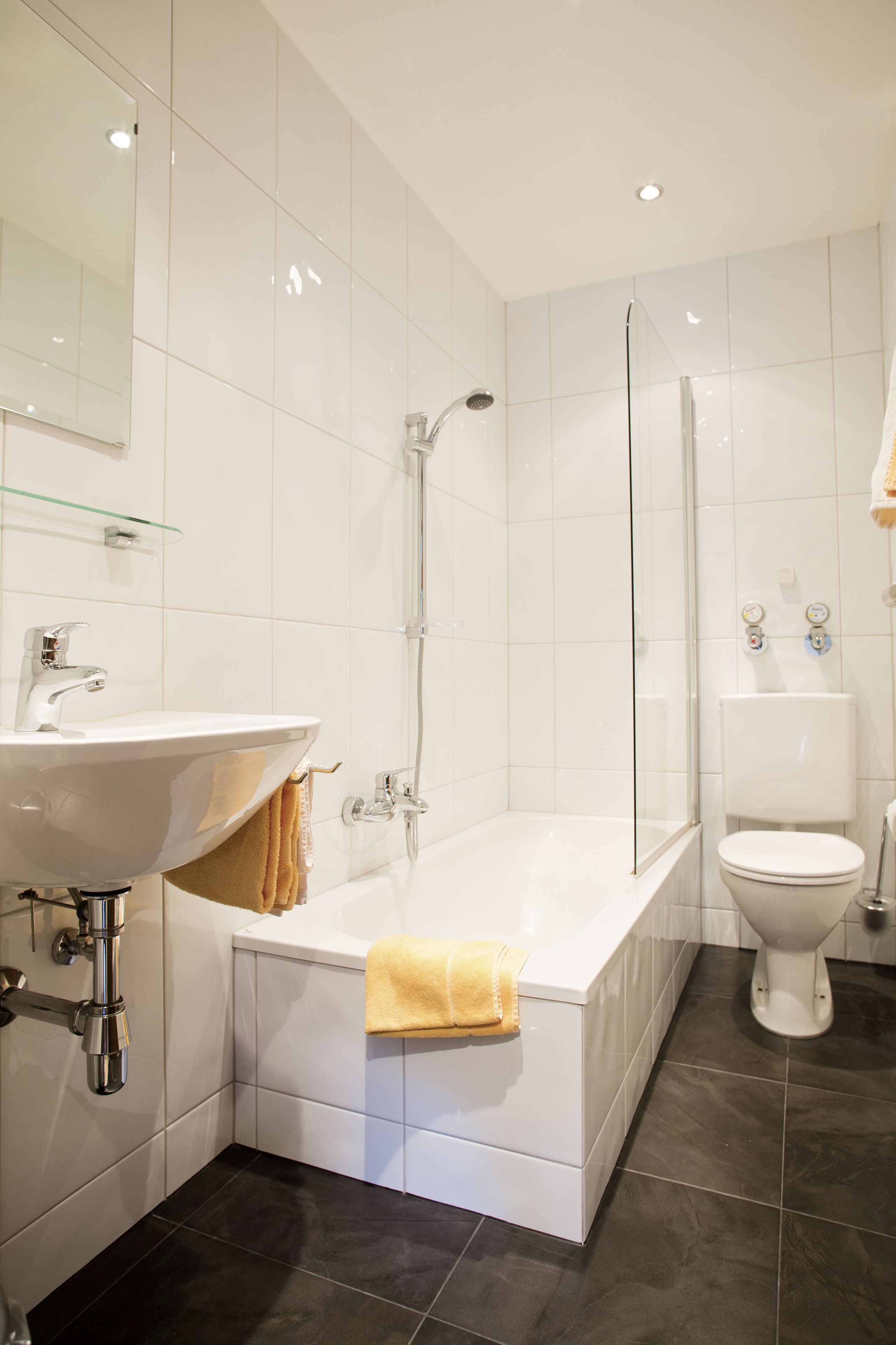 Een moderne badkamer met een wit wastafelmeubel, bad en toilet.