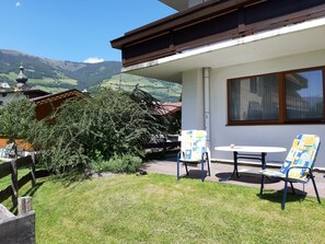 A patio with two chairs and a table, a wooden fence, and a view of a mountain landscape. - Alphotel Mittersill (Mittersill)
